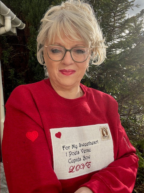Person wearing a red sweatshirt with a printed message and heart designs.